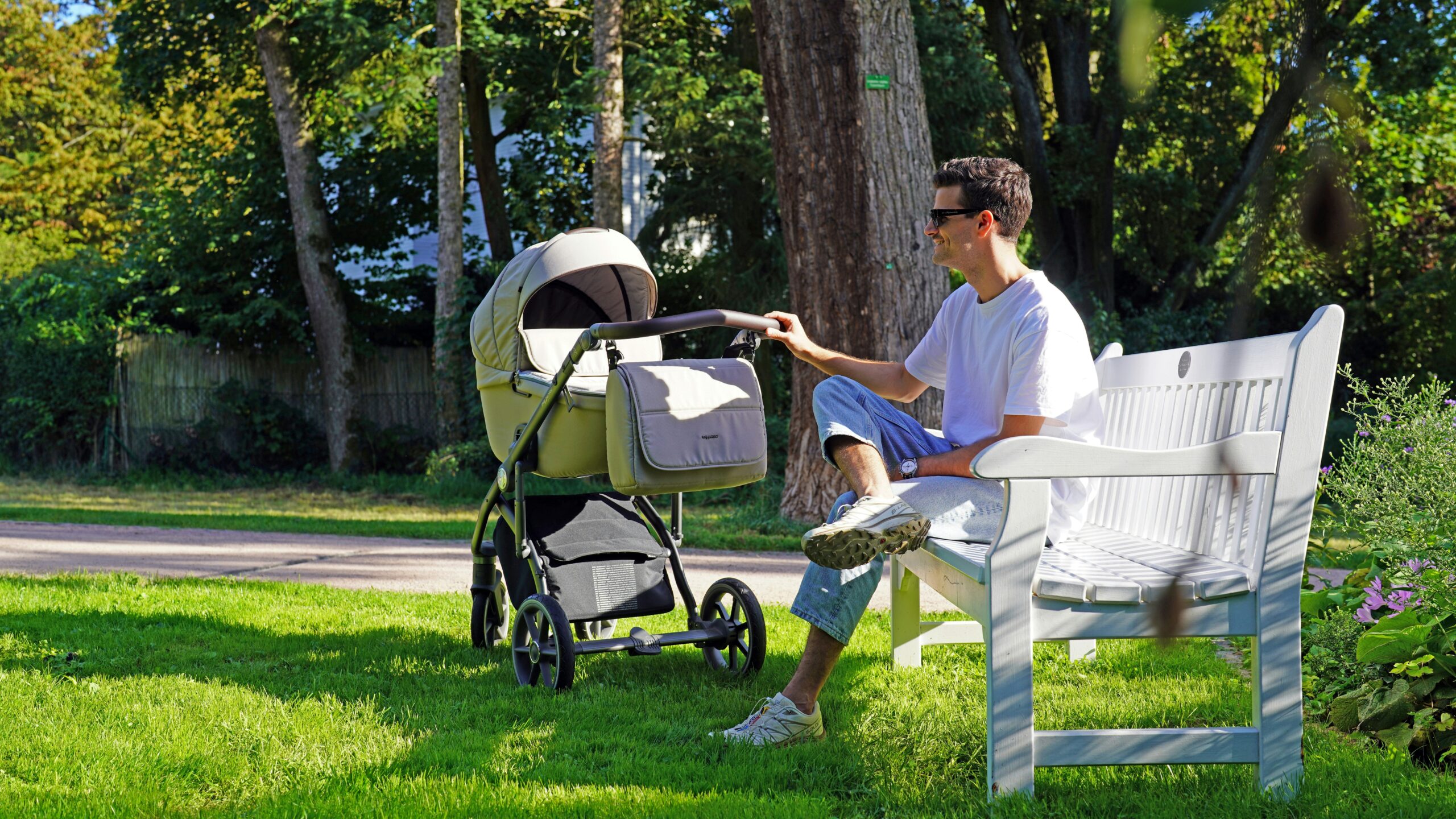 a man sitting on a bench next to a baby stroller
