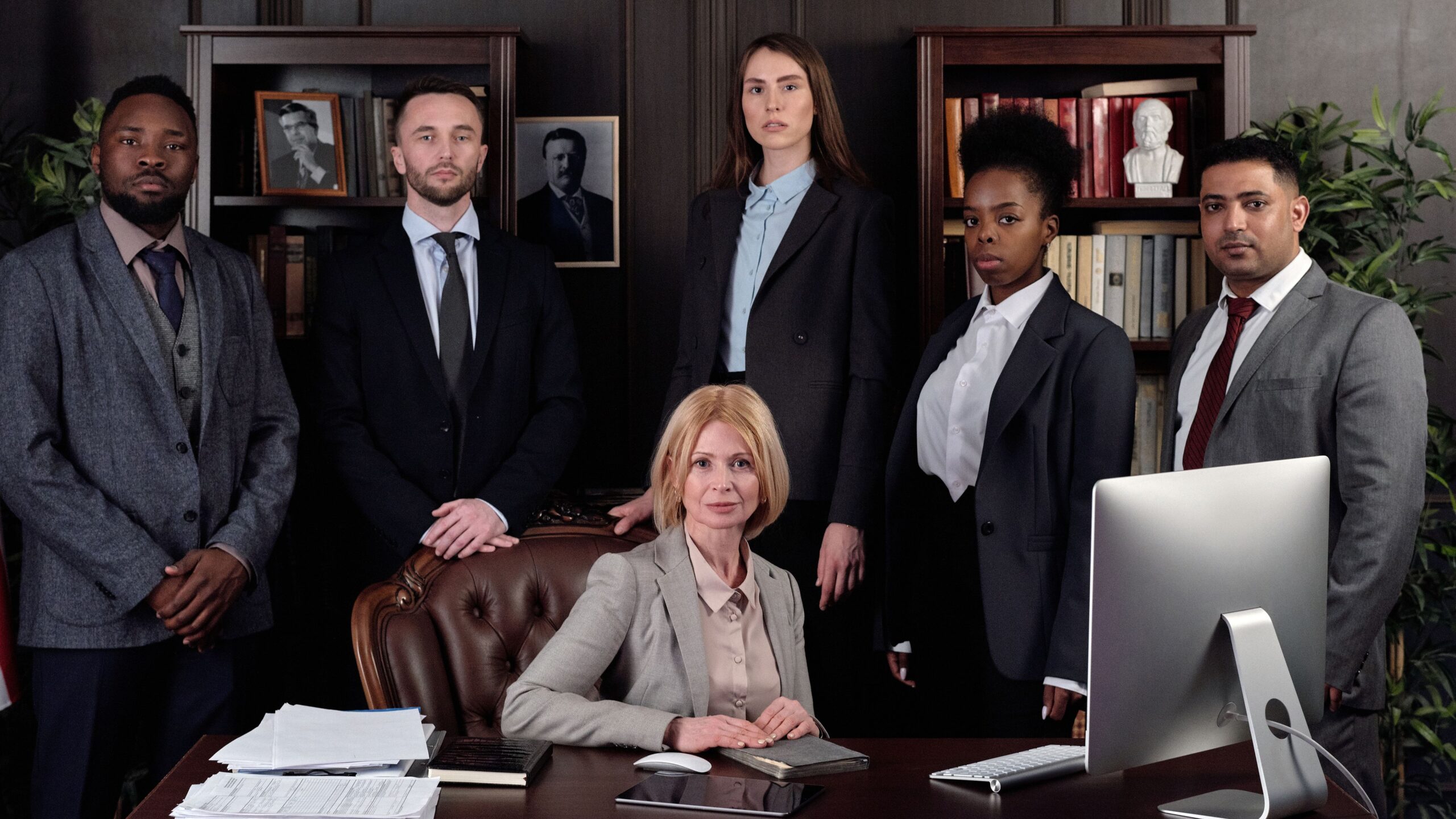 Diverse group of professionals in corporate attire posing confidently in an office environment.