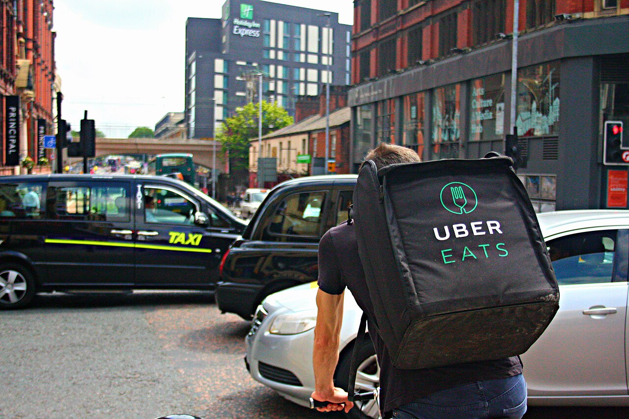 A food-delivery cyclist rides through city traffic