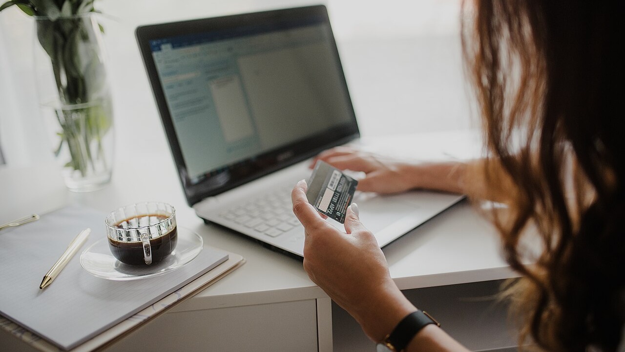 A woman holding a credit card while using a laptop