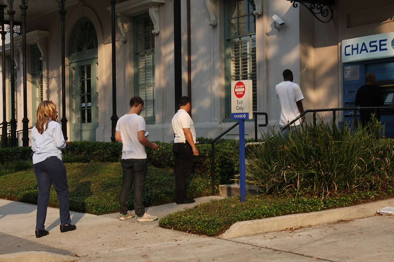 Customers line up at an ATM