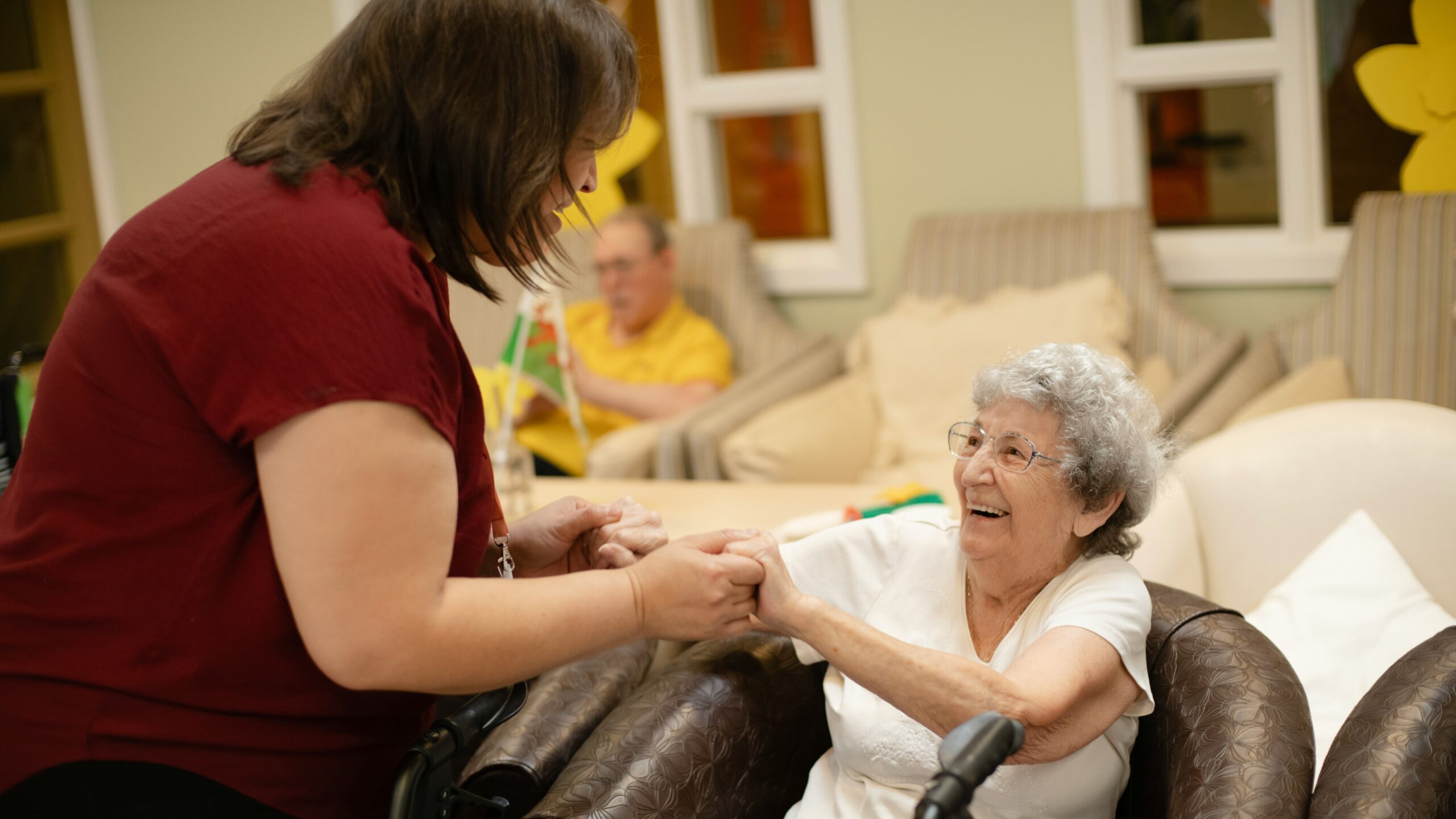 Caregiver assists elderly woman with walker.