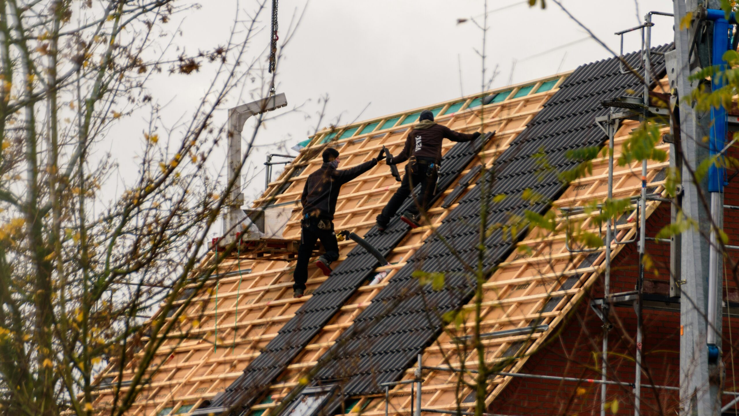 Construction workers installing roofing materials on a house.