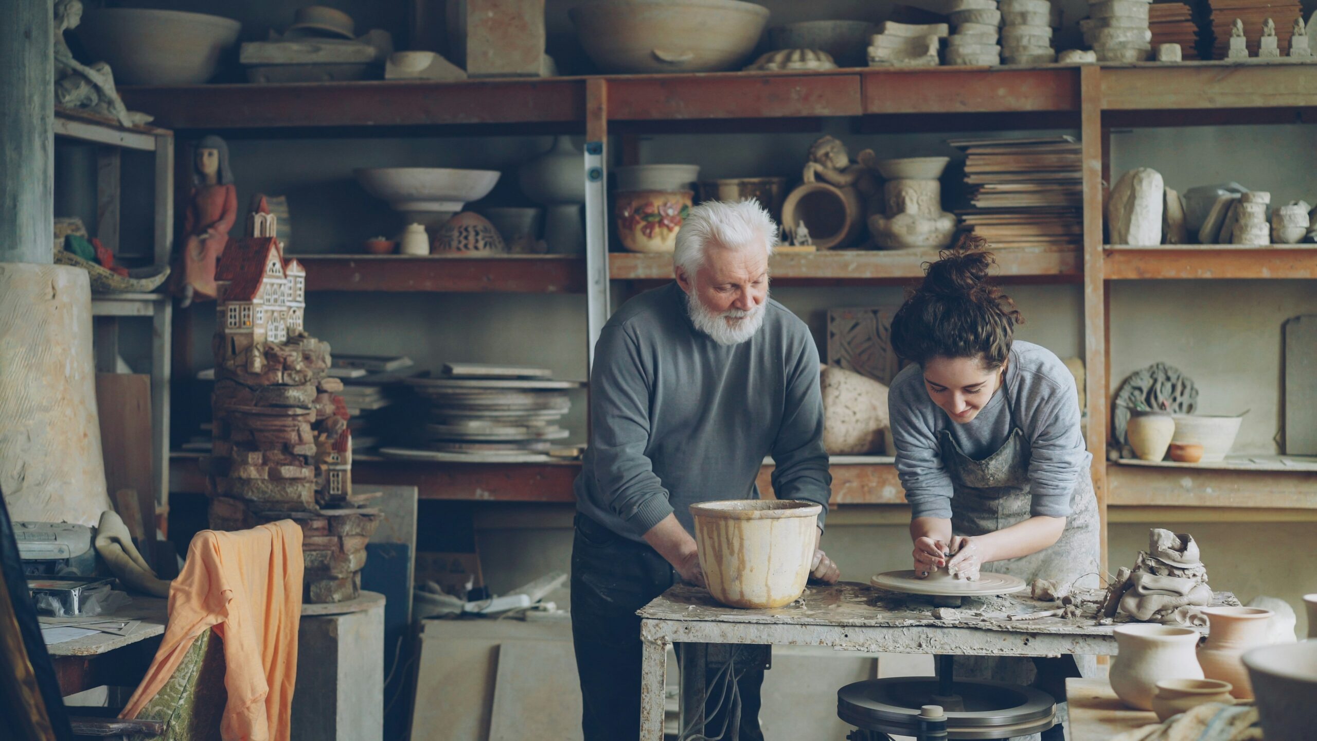A potter and an apprentice work in a workshop.