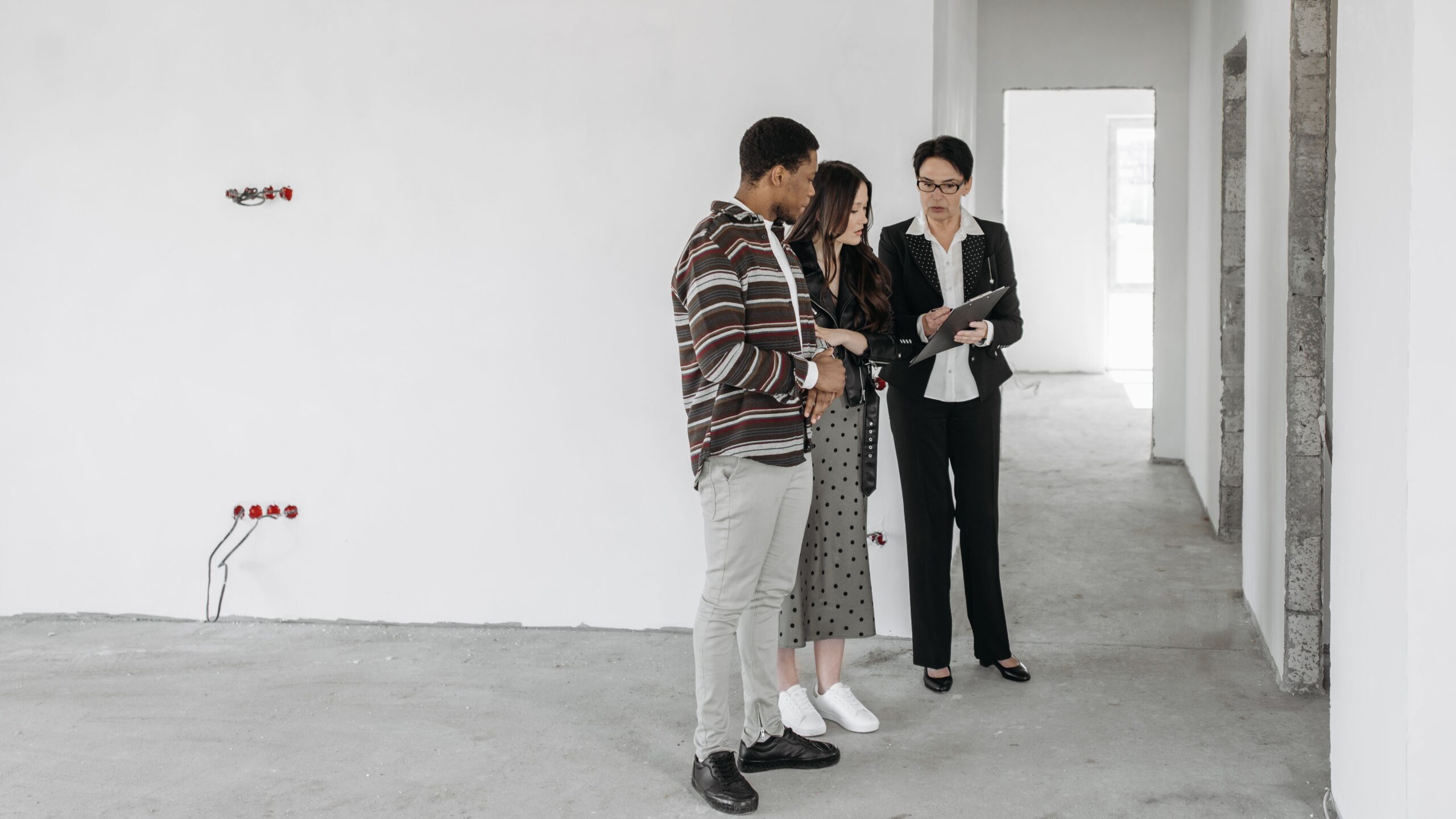 A couple and realtor discuss details in an unfinished property. Ideal for real estate themes.
