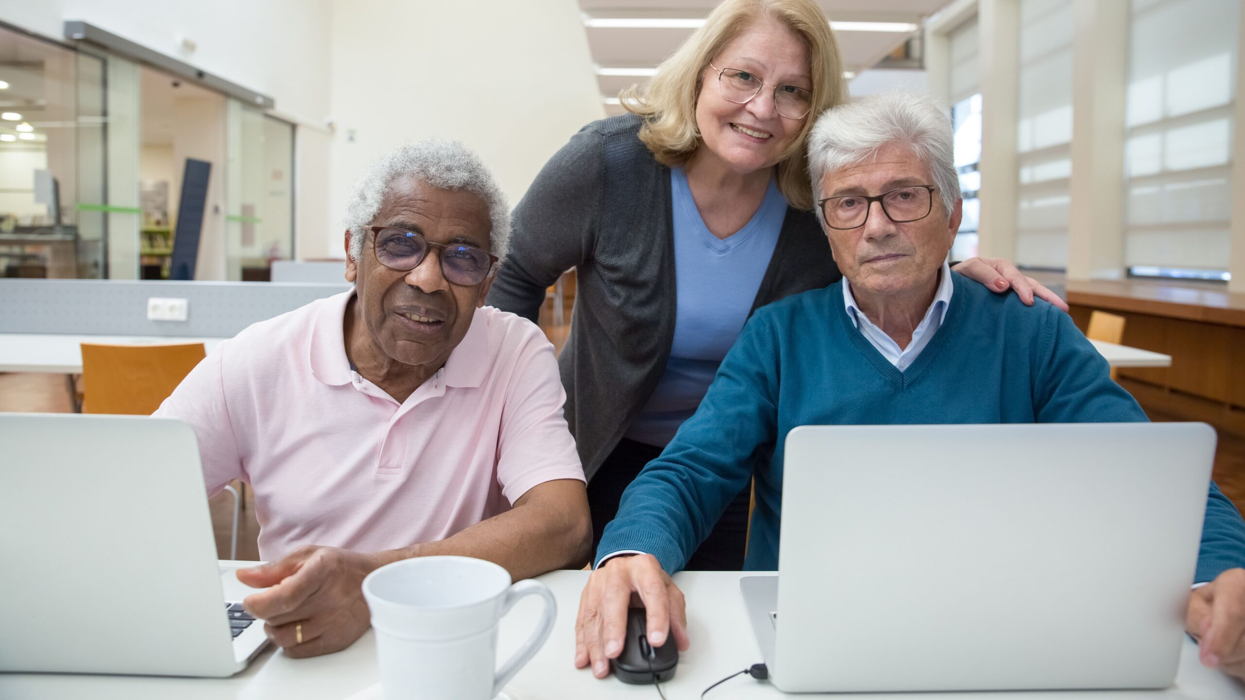 Elderly adults learning and enjoying computer class together indoors.