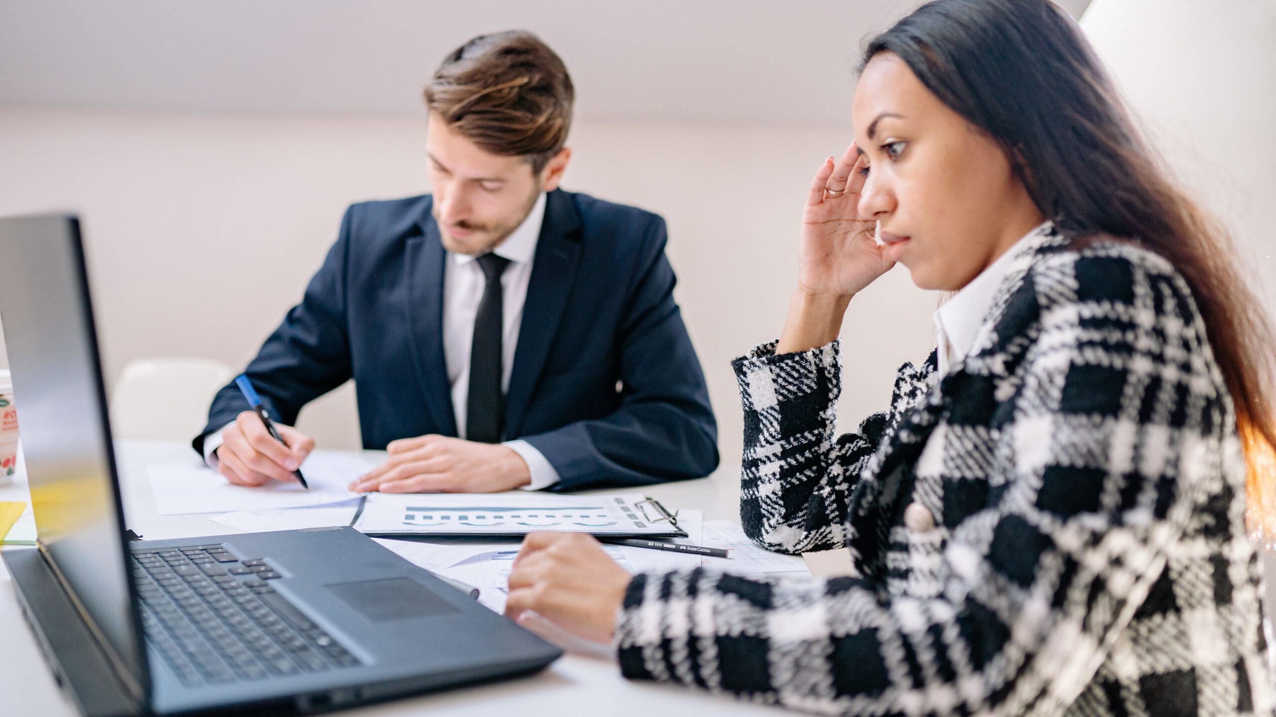 Two business professionals working together in an office, focusing on a project.